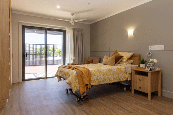 A bright Superior Room at Strathpine Aged Care, featuring warm timber finishes, floor-to-ceiling windows, and private patio access.