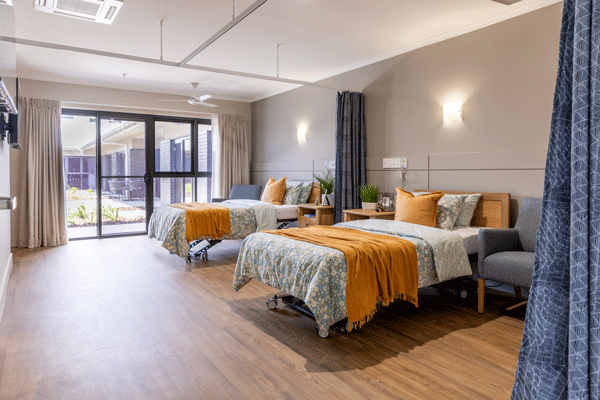 A spacious Superior Shared Room at Strathpine Aged Care, featuring twin beds with vibrant bedding and floor-to-ceiling windows for plenty of natural light.